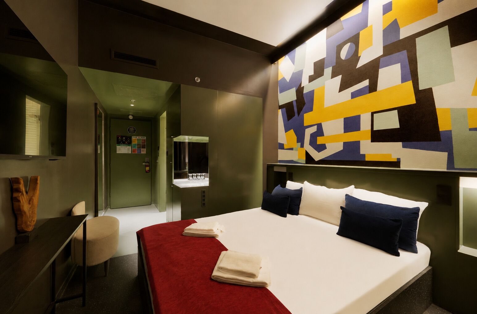 Una habitación de hotel moderna con una cama, un escritorio y un cuadro abstracto grande en la pared.