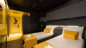 A hotel room with two beds, a desk, and a bathroom.