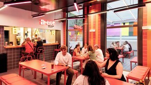 A modern interior with red furniture, a bar area, and large windows allowing natural light. - AMISTAT Hub Hostel Budapest (Budapest)