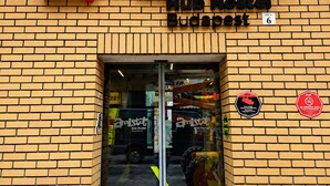Une enseigne « Hub Hostel Budapest » avec un logo rouge et noir, une façade en briques et une entrée en verre.