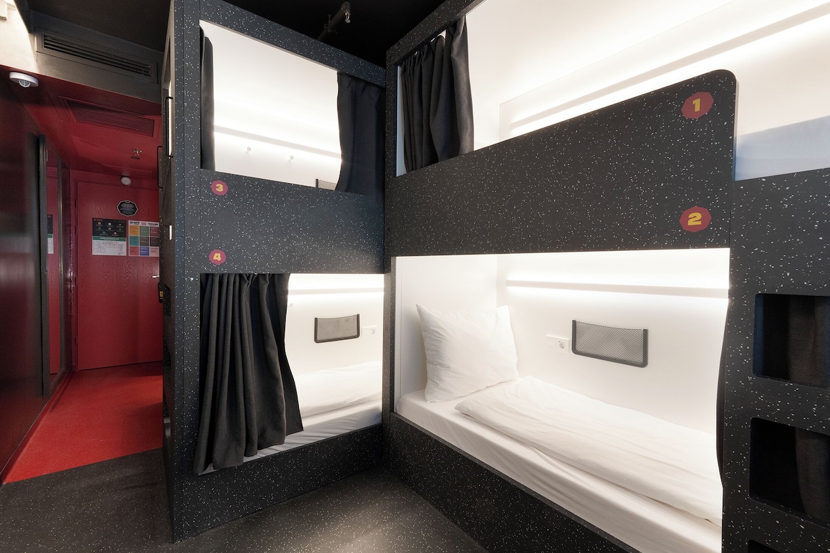 A hotel room with bunk beds, a red carpet, and a security camera.