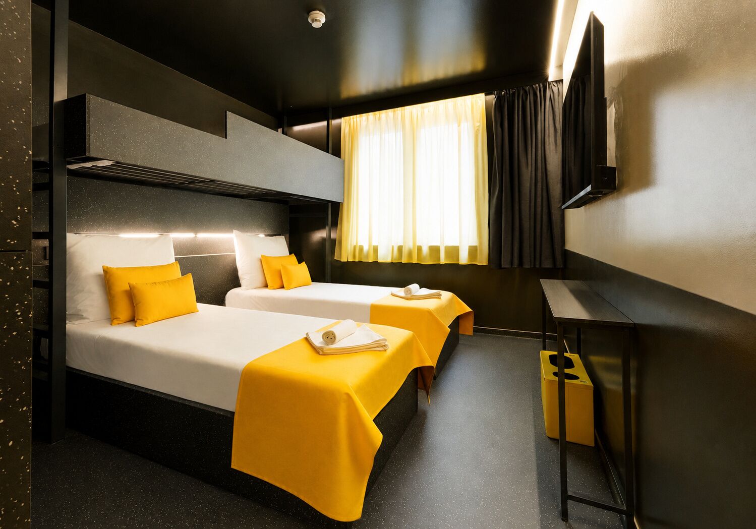 A hotel room with two beds, a flat-screen TV, a small table, and a window with curtains.