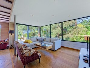 Ein modernes Wohnzimmer mit großem Fenster, einer Couch, einem gemusterten Sessel und einem Couchtisch.