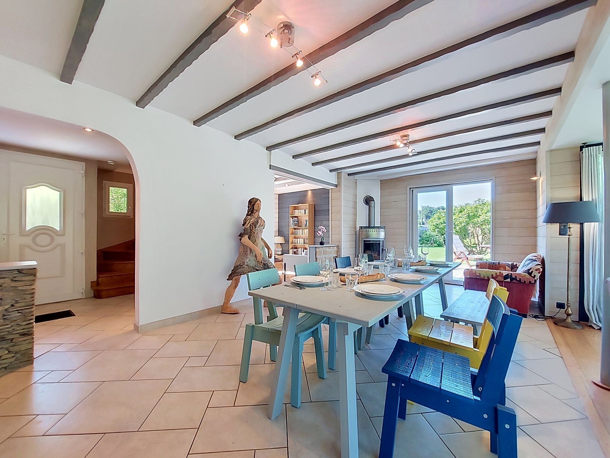 A modern dining area with a long table, blue chairs, and a fireplace.