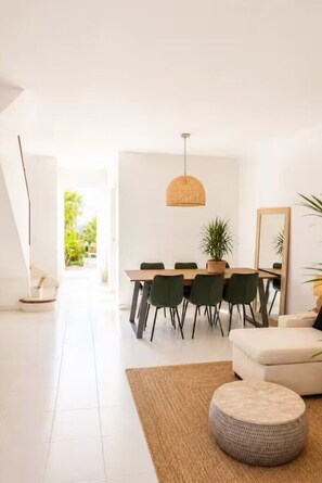 A modern dining area with a table, chairs, and a hanging light fixture.