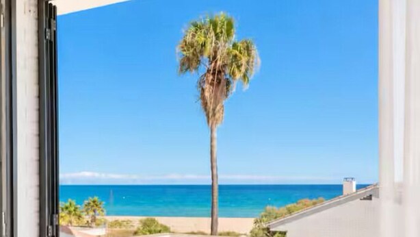 Una habitación con puerta de vidrio que da a un balcón con vistas a la playa y al océano.