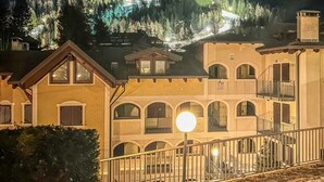 A hotel with a courtyard, a staircase, and a mountain backdrop. - Le Ville Apartment - Ponte di Legno (Ponte di Legno)