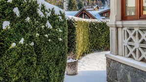 A snow-covered pathway leading to a building with a mountain view. - Le Ville Apartment - Ponte di Legno (Ponte di Legno)