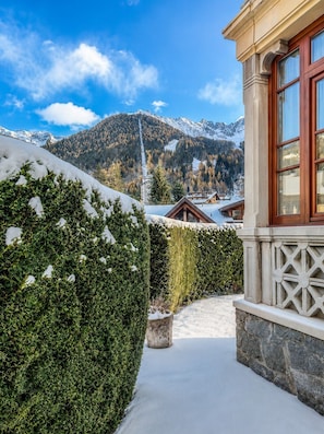 Ein verschneiter Pfad, der zu einem Gebäude mit Bergblick führt.