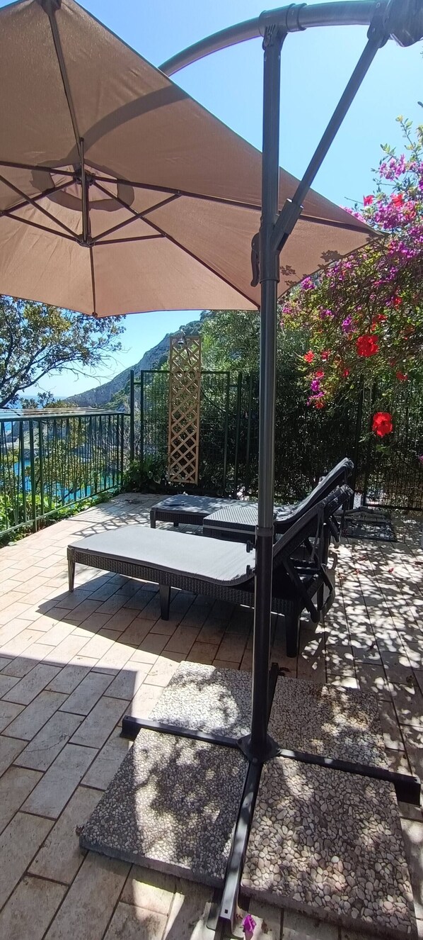 Une terrasse avec une table et des chaises, une pergola avec un auvent et une vue sur un paysage montagneux.