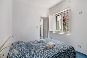 Ein Schlafzimmer mit Bett, einem Fenster mit Ausblick und einer Tür zu einem weiteren Raum.