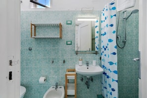 Ein Badezimmer mit Waschbecken, Spiegel, Dusche und Handtuchhalter.