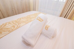 Ein ordentlich bezogenes Bett mit einem gefalteten Handtuch und einem Zierkissen.