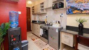 A compact kitchen with a water dispenser, a stove, a microwave, and a refrigerator. - Studio in Nairobi South B (Nairobi)