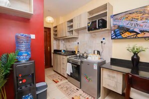 Eine kleine Küche mit Wasserspender, Herd, Mikrowelle und Kühlschrank.