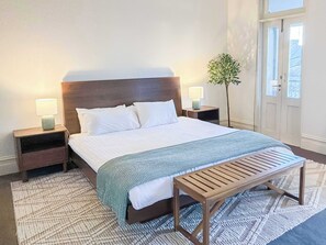 A neatly made bed with white linens, two bedside tables with lamps, a bench, and a potted plant. - Huge Heritage Terrace, Walk to KX, Parking, BBQ (Darlinghurst)