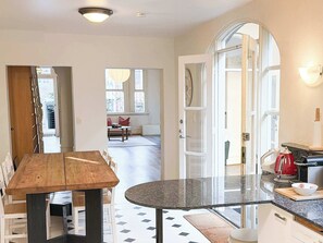 A modern kitchen with a wooden dining table, a round island, and a red kettle. - Huge Heritage Terrace, Walk to KX, Parking, BBQ (Darlinghurst)
