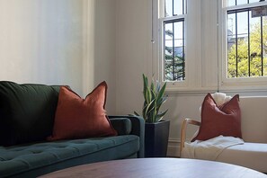 A room with a green sofa, a potted plant, and a window with a view of trees. - Huge Heritage Terrace, Walk to KX, Parking, BBQ (Darlinghurst)