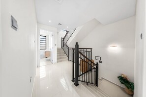 A modern interior with a staircase, a white door leading to a bathroom, and a potted plant.