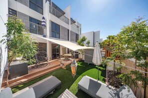 A modern outdoor patio with a dining area, lounge chairs, and a decorative lantern.
