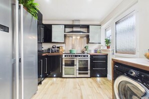 A compact kitchen with a built-in oven, a washing machine, and a window with frosted glass.