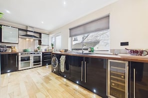 A modern kitchen with a central island, built-in oven, and a large window.