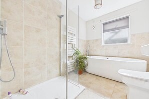 A modern bathroom with a glass shower enclosure, a freestanding bathtub, and a white toilet.
