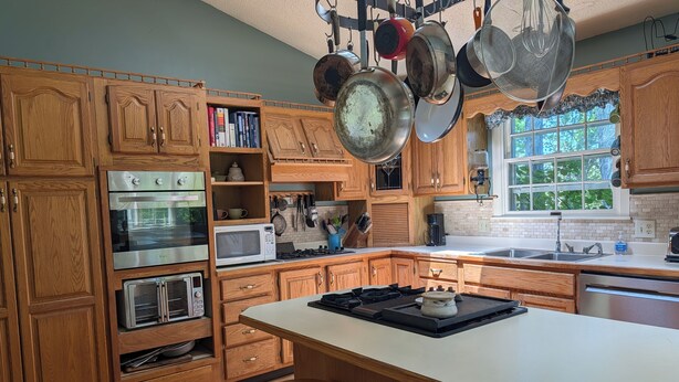 A kitchen with wooden cabinets, stainless steel appliances, and a large island with stools.