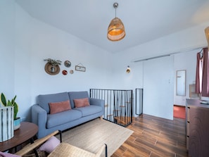 Un salon moderne avec un canapé, une table à manger et un luminaire suspendu.