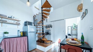 Una cucina moderna con una scala a chiocciola, pavimento in legno e un'area pranzo con sedie rosse.
