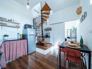 Una cocina moderna con una escalera de caracol, piso de madera y un comedor con sillas rojas.