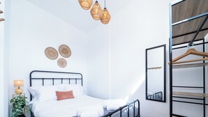 Una camera da letto ordinata con un letto, una lampada da comodino, cesti a parete e uno specchio.