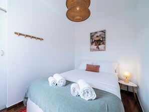 Une chambre d’hôtel avec un lit, une lampe de chevet, un porte-serviettes fixé au mur et un tableau.