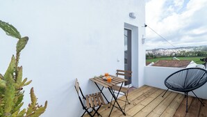Un balcone con tavolo e sedie, una pianta di cactus e vista su una città.