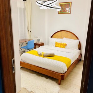 Ein ordentlich eingerichtetes Schlafzimmer mit einem hölzernen Bett, einem kleinen Nachttisch, einem Sessel und einer Wandleuchte.