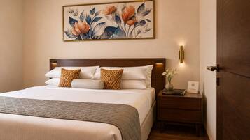 A neatly made bed with a quilted blanket, a wooden headboard, and a nightstand with a book and a vase of flowers.