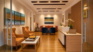 A modern reception area with a reception desk, seating area with two sofas, and artwork on the walls. - Parijaat Parisar (Vrindavan)