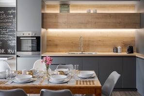 A modern kitchen with a built-in oven, a stainless steel sink, and a wooden countertop.