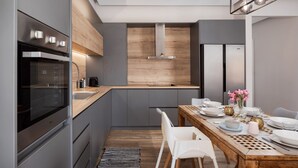 Eine moderne Küche mit Backofen, einer Holzauskład und einem Essbereich mit Tisch für vier Personen.