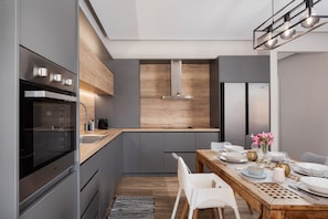 A modern kitchen with a built-in oven, a wooden countertop, and a dining area with a table set for four.