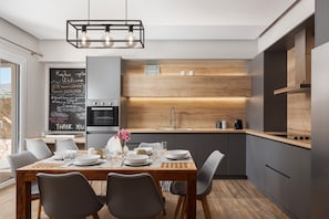 A modern kitchen with a wooden island, a chalkboard with writing, and a dining area with a table set for two.