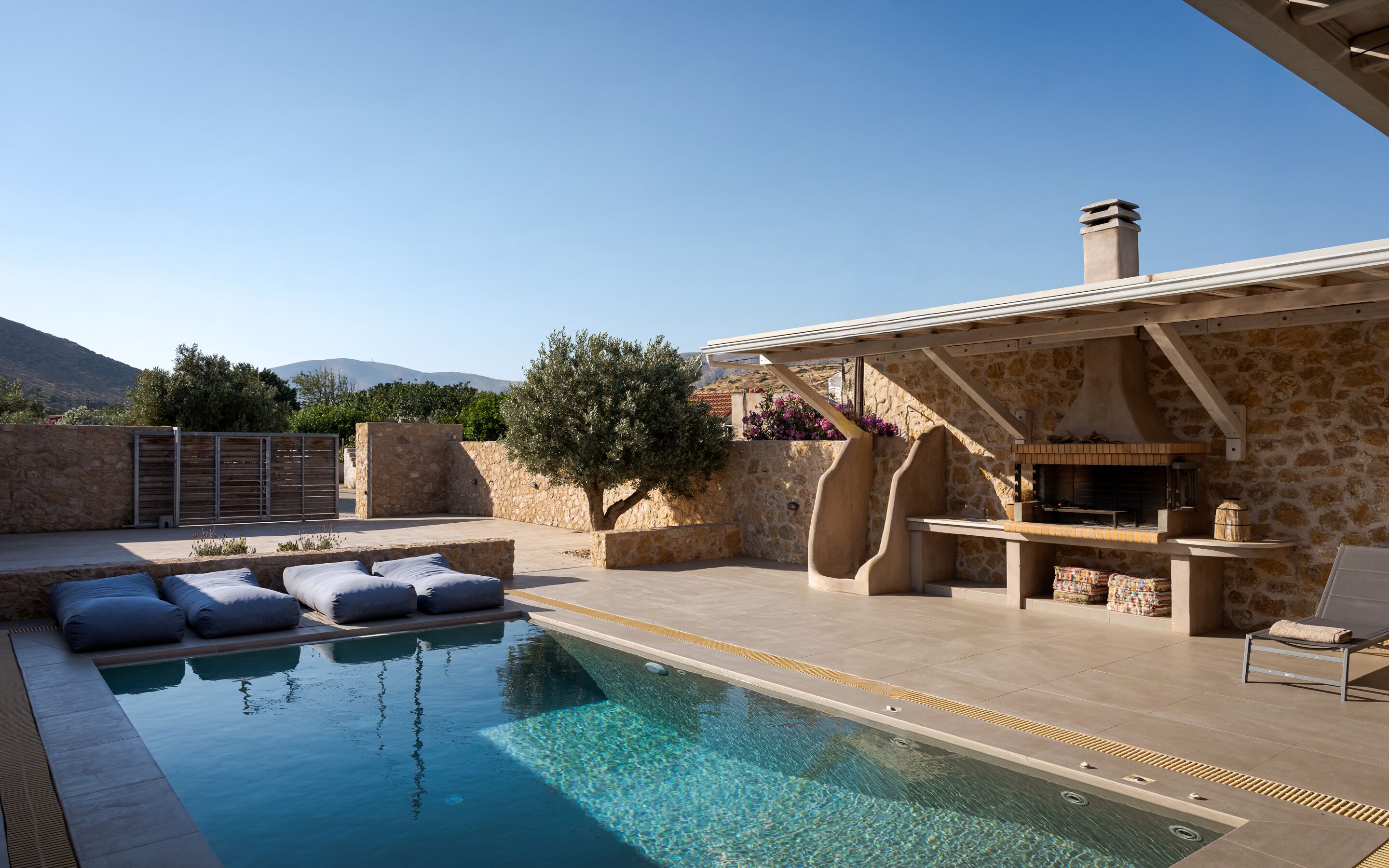 Una piscina con muro de piedra, mobiliario exterior y zona de barbacoa.