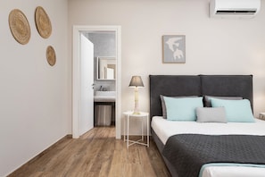 A bedroom with a bed, bedside table, lamp, and wall decor.