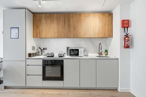 Eine moderne Küche mit weißen Schränken, einer Holzablage, einer Mikrowelle, einem Toaster und einem Geschirrspüler.