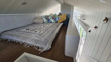 A room with a bed, a patterned rug, and a wall-mounted shelf with hooks.