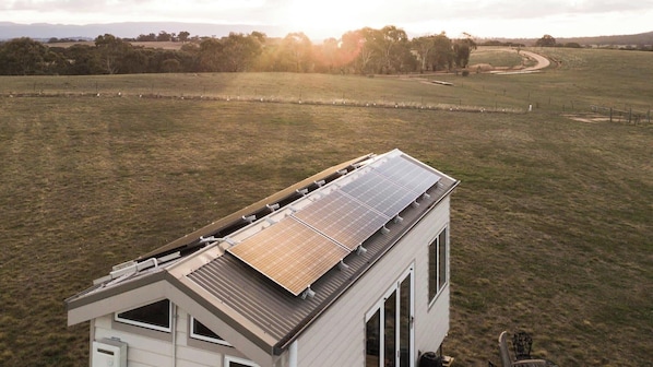 Un edificio con techo de paneles solares y vista a un paisaje rural.