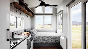 Un dormitorio pequeño con cama, ventana y kitchenette.