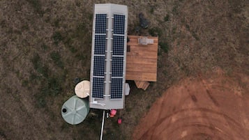 A solar panel installation with a wooden structure, a water tank, and a dirt area.