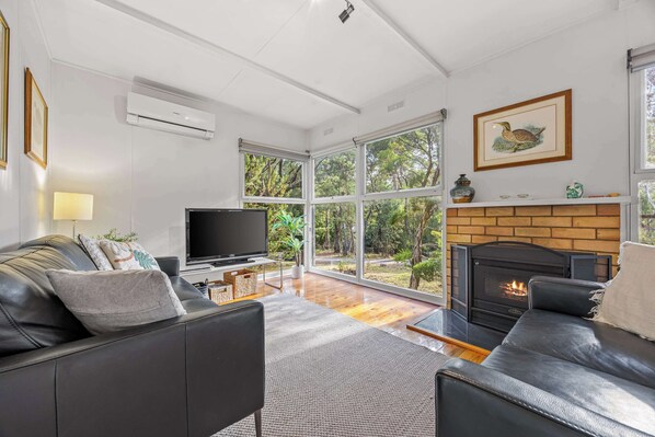 A modern living room with a fireplace, a television, and a sofa.