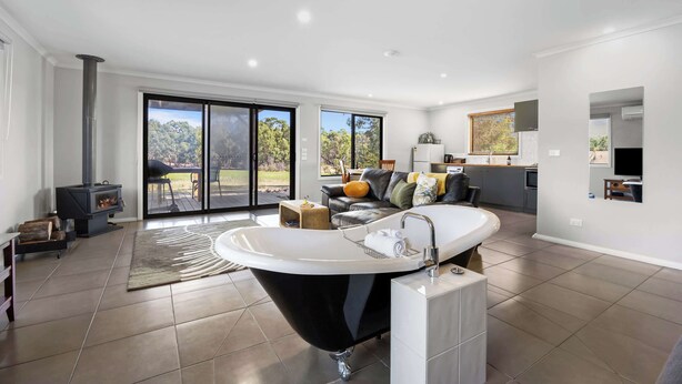 A modern bathroom with a freestanding bathtub, a large window, and a view of the outdoors.